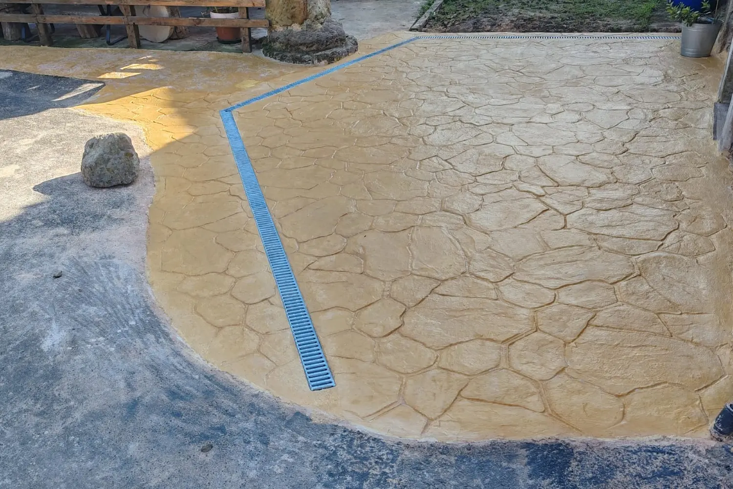 Patio de hormigón impreso con textura de piedra y canaleta de drenaje